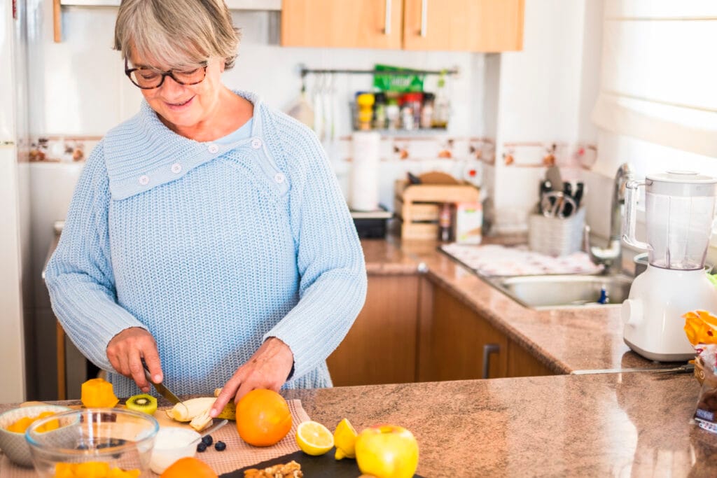 grandmother with glasses cut fruit and smiling - lifestyle healt