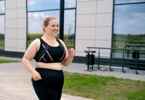 A plump young blonde woman in a sports uniform runs along the sidewalk